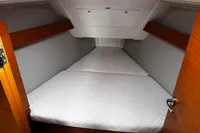 2022 Dufour 32 yacht cabin with white mattress and wooden accents.