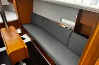 Interior of 2022 Dufour 32 yacht with gray sofa and wooden accents.