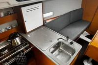 Modern kitchen area in 2022 Dufour 32 yacht with sink, stove, and seating.