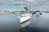 2022 Dufour 32 sailboat docked in a marina under cloudy skies.