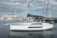 2022 Dufour 32 sailboat docked in a marina under cloudy skies.