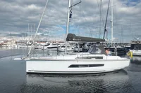 2022 Dufour 32 sailboat docked in a marina under cloudy skies.
