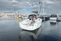 2022 Dufour 32 sailboat "Le Corbeau" in marina, cloudy sky, calm water.