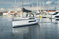 2022 Dufour 32 sailboat docked in a marina, surrounded by other boats.