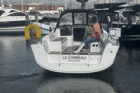 2022 Dufour 32 sailboat "Le Corbeau" in marina, rear view with person onboard.
