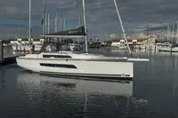 2022 Dufour 32 sailboat docked in a marina under cloudy skies.