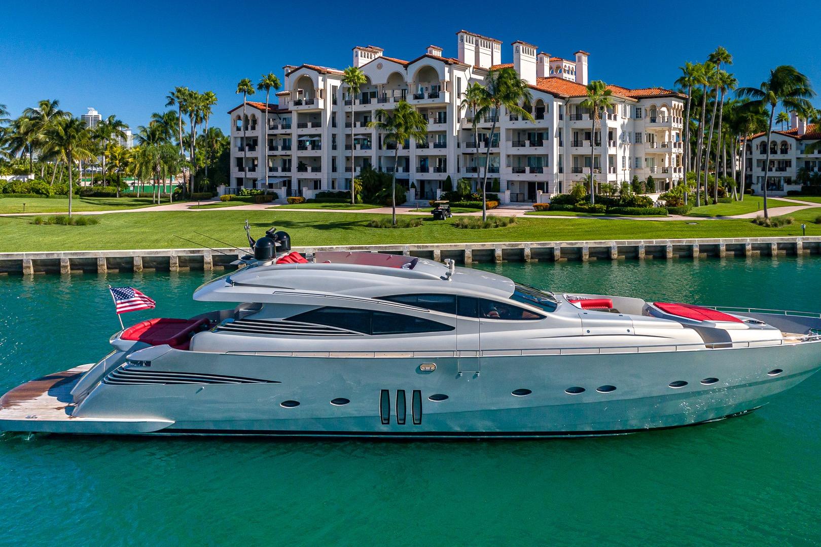 Luxury 2008 Pershing 90 yacht docked near waterfront residences, surrounded by palm trees.