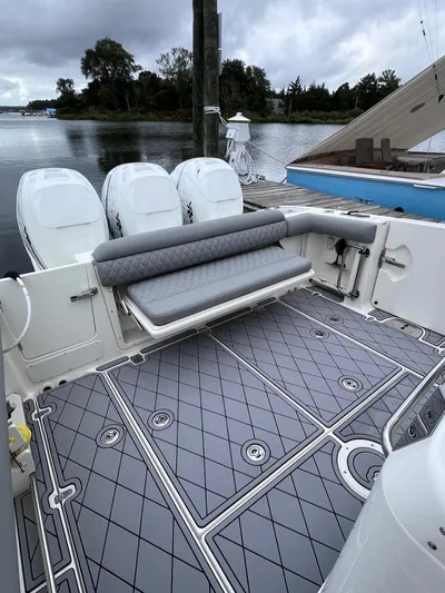  Yacht Photos Pics 2018 Boston Whaler 350 Outrage boat with triple engines and cushioned seating, docked by a serene lake.
