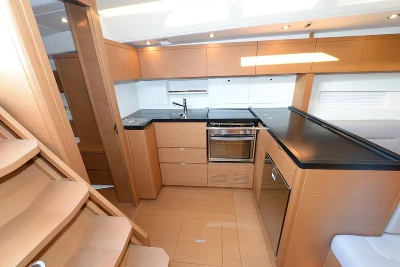 Yacht Photos Pics Modern kitchen interior of 2019 Grand Soleil 48 Performance yacht, featuring sleek wood cabinetry.