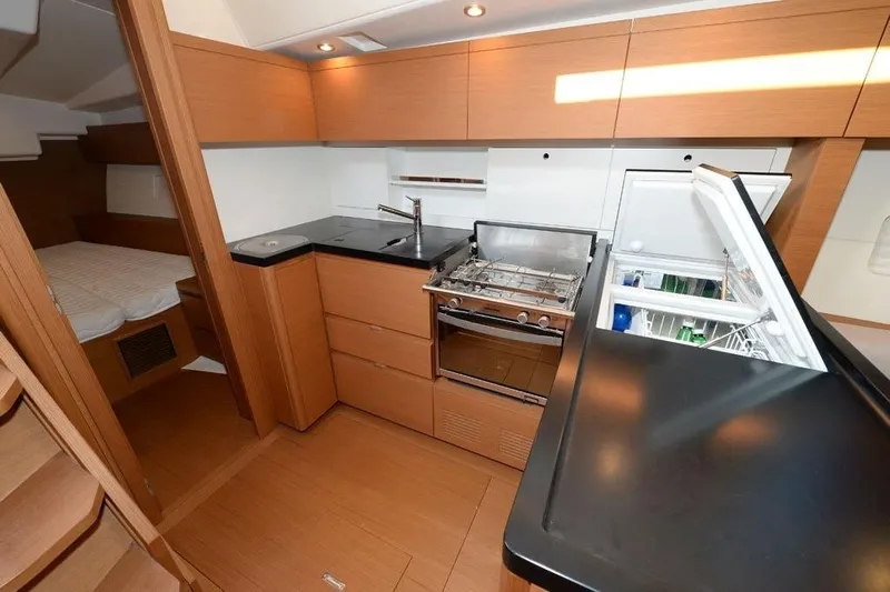  Yacht Photos Pics Modern kitchen interior of 2019 Grand Soleil 48 Performance yacht with wood finish and appliances.