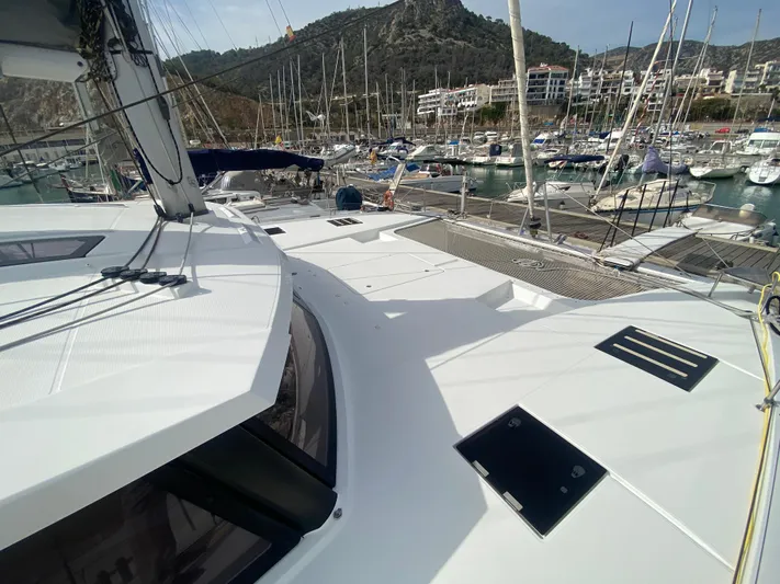 Luna Yacht Photos Pics 2020 Fountaine Pajot Saona 47 catamaran docked in a marina with mountainous backdrop.