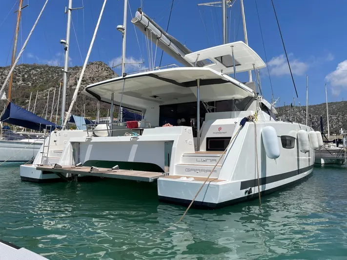 Luna Yacht Photos Pics 2020 Fountaine Pajot Saona 47 catamaran docked in a marina, clear sky background.