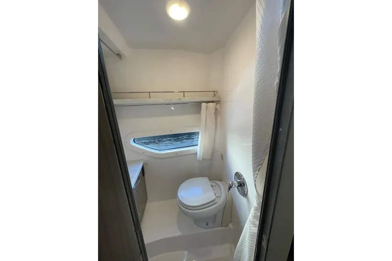 Then Again Yacht Photos Pics 2021 Regal 33 XO boat bathroom with toilet, window, and shower curtain.