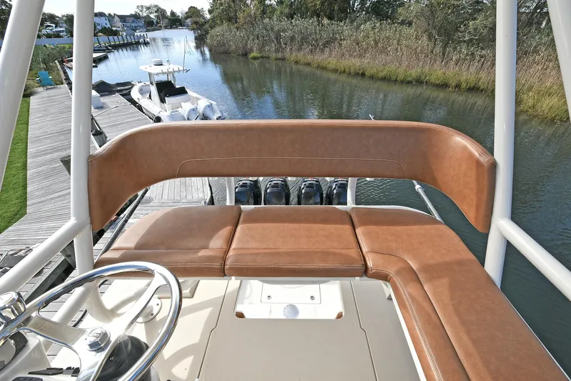  Yacht Photos Pics 2016 Scout 420 LXF boat interior with brown seating and steering wheel, docked by a serene waterway.