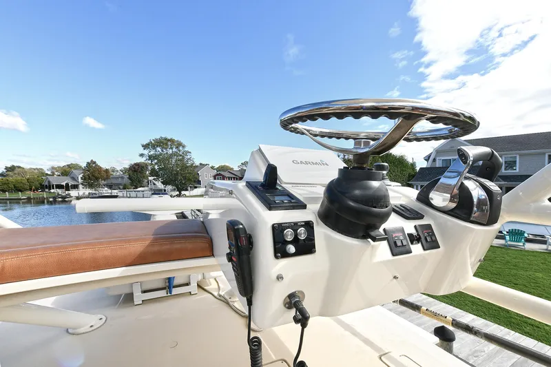  Yacht Photos Pics Helm of 2016 Scout 420 LXF boat with steering wheel and controls, docked by waterfront homes.