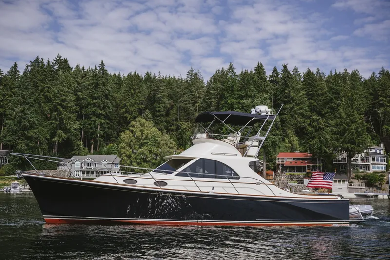 Mm Yacht Photos Pics San Juan SJ40FB IPS 2010 yacht on water, surrounded by forested shoreline and houses.