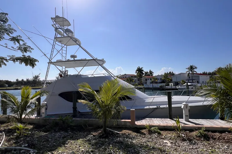 Renegade Yacht Photos Pics 2001 Hatteras 65 Convertible yacht docked by palm trees under clear blue sky.