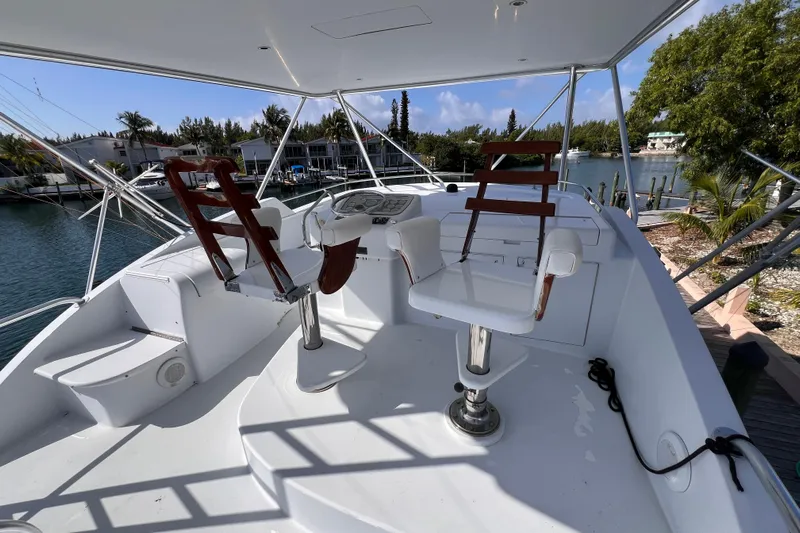 Renegade Yacht Photos Pics Flybridge of 2001 Hatteras 65 Convertible yacht with helm chairs and scenic marina view.