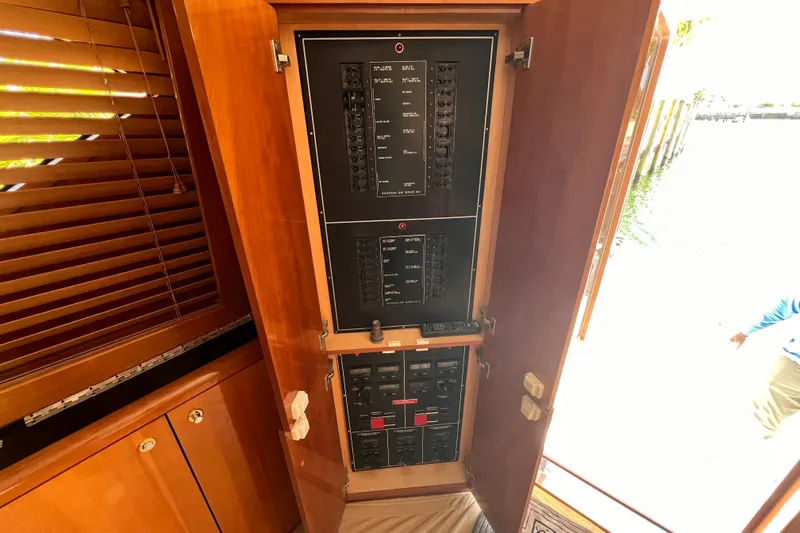 Renegade Yacht Photos Pics Electrical panel inside 2001 Hatteras 65 Convertible yacht, featuring wooden cabinetry and control switches.