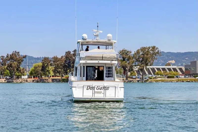 Ds Gatos Yacht Photos Pics A 1999 Symbol 558 yacht cruising on a scenic waterway with trees and buildings in the background.