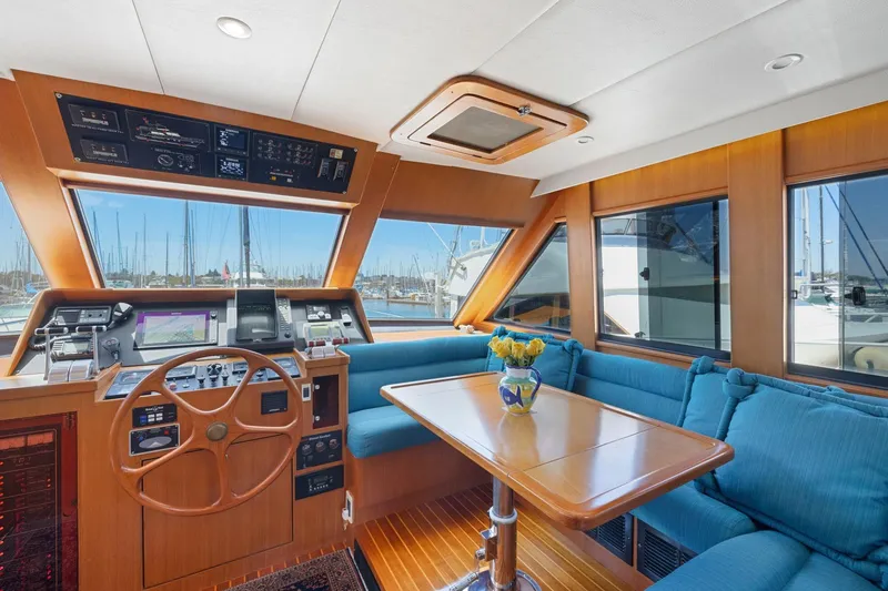 Ds Gatos Yacht Photos Pics Luxurious 1999 Symbol 558 yacht interior with helm, blue seating, and wooden table.