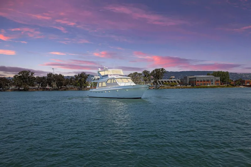 Ds Gatos Yacht Photos Pics Luxury yacht Symbol 558, 1999 model, cruising at sunset with scenic shoreline backdrop.