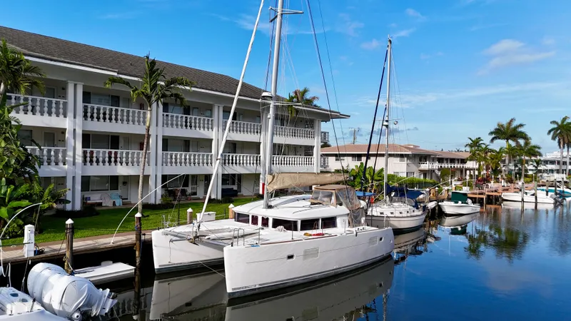 Selkie Yacht Photos Pics 2012 Lagoon 400 catamaran docked near waterfront apartments, surrounded by palm trees.