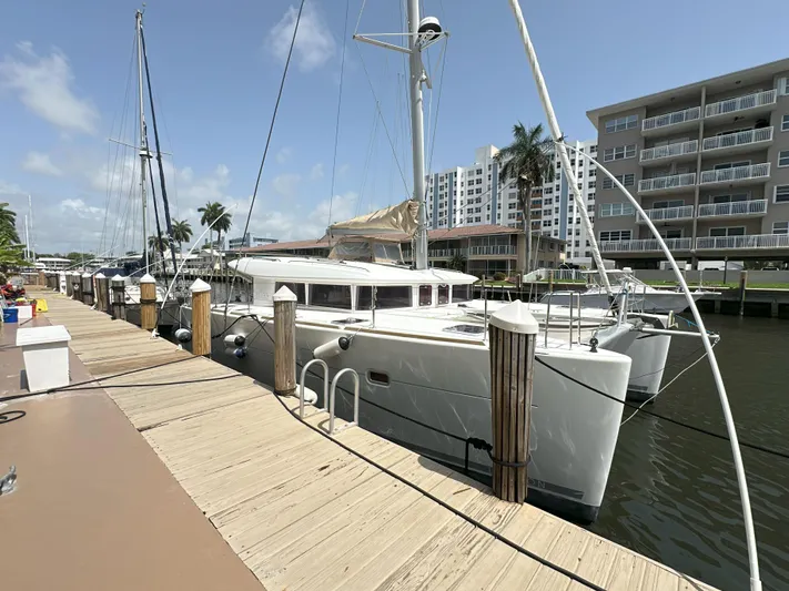 Selkie Yacht Photos Pics 2012 Lagoon 400 catamaran docked at marina, surrounded by modern buildings and palm trees.