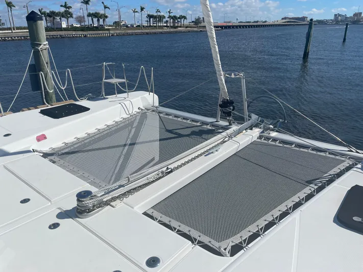 Sun Bums Yacht Photos Pics 2017 Lagoon 39 catamaran with netted deck, docked by calm waters and palm trees.