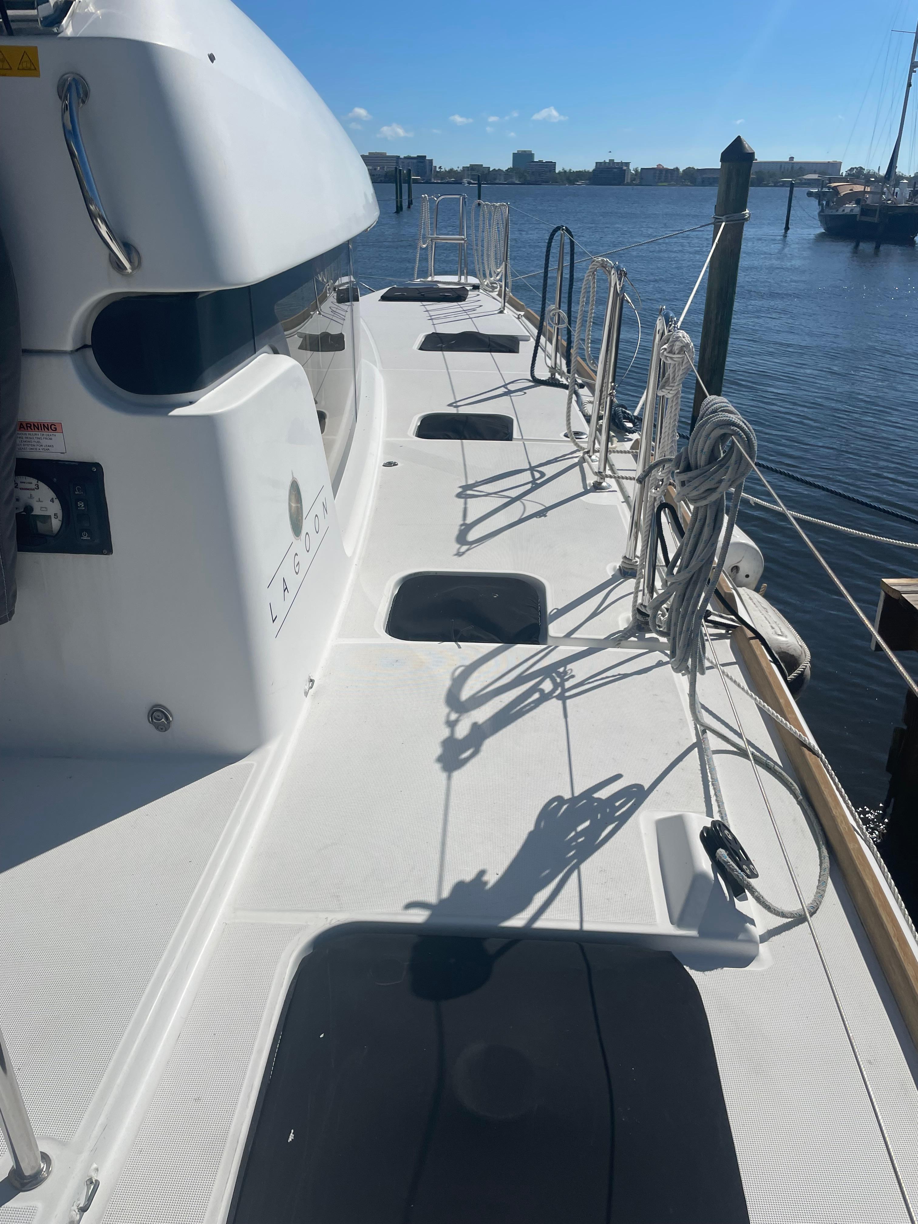 2017 Lagoon 39 catamaran deck with ropes, docked at marina under clear blue sky.