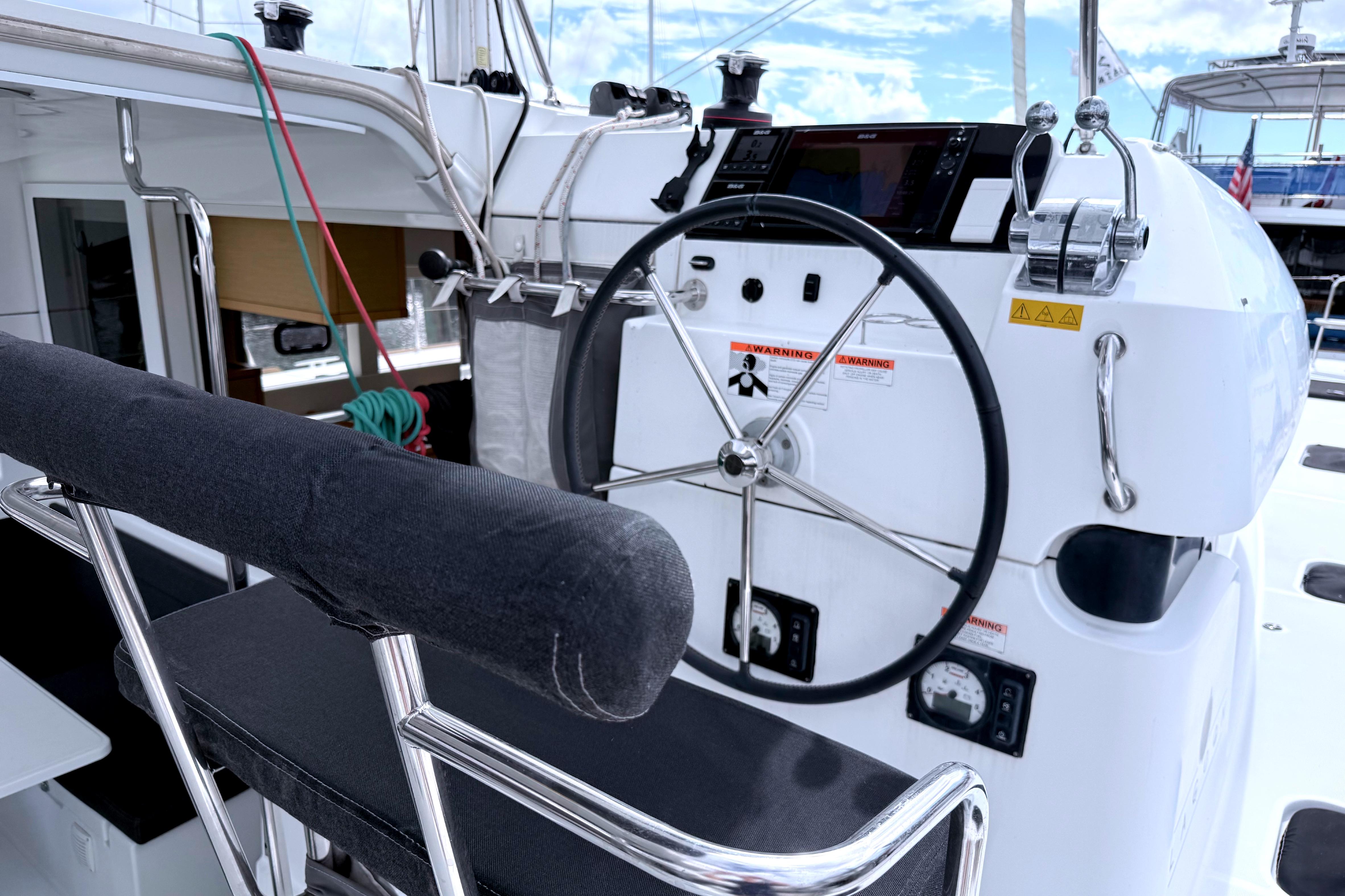 Steering wheel and controls of a 2017 Lagoon 39 catamaran, featuring modern navigation equipment.