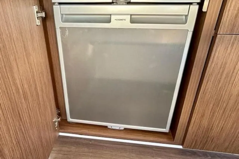  Yacht Photos Pics Built-in refrigerator on 2024 Beneteau Antares 9 boat, featuring wooden cabinetry.
