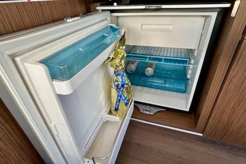  Yacht Photos Pics Compact refrigerator inside 2024 Beneteau Antares 9 boat, featuring drinks and storage.