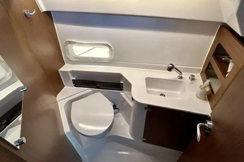  Yacht Photos Pics 2024 Beneteau Antares 9 bathroom interior with sink, toilet, and wooden accents.