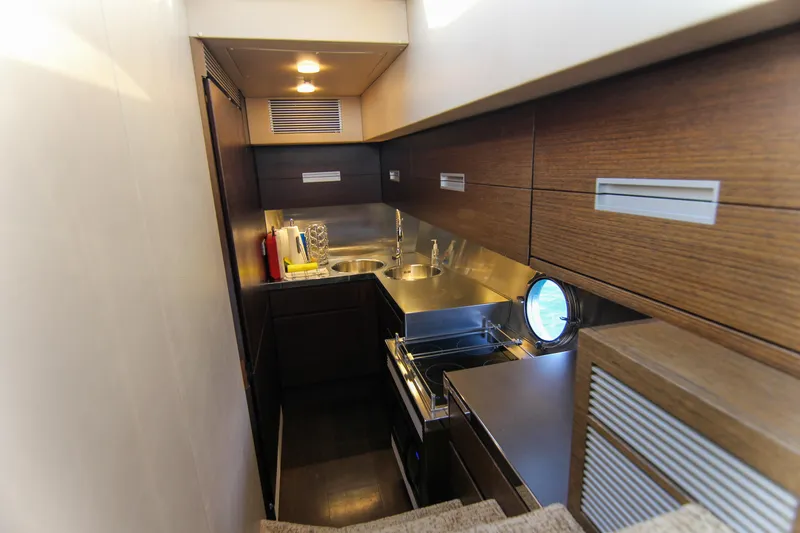  Yacht Photos Pics Compact kitchen area in a 2006 Azimut 68S yacht, featuring modern wood cabinetry and stainless steel fixtures.