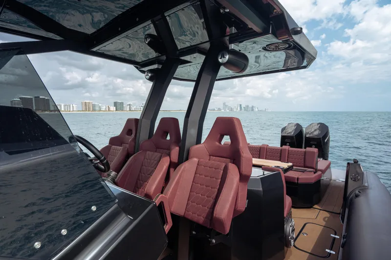  Yacht Photos Pics Luxury Skipper-BSK 42NC boat interior with red seats, ocean view, and city skyline in background.