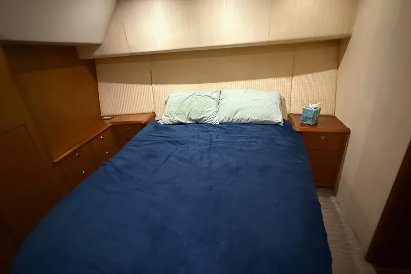Trolling Fever Yacht Photos Pics Cozy bedroom in 2005 Ocean Yachts 46 Super Sport with blue bedding and wooden cabinets.