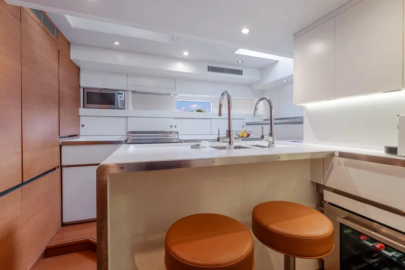 Cloudy Night Yacht Photos Pics Modern yacht kitchen interior with sleek design, featuring dual sinks, bar stools, and built-in appliances.