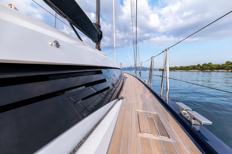 Cloudy Night Yacht Photos Pics Sleek CNB 76 yacht deck, 2019 model, sailing on calm waters under a blue sky.