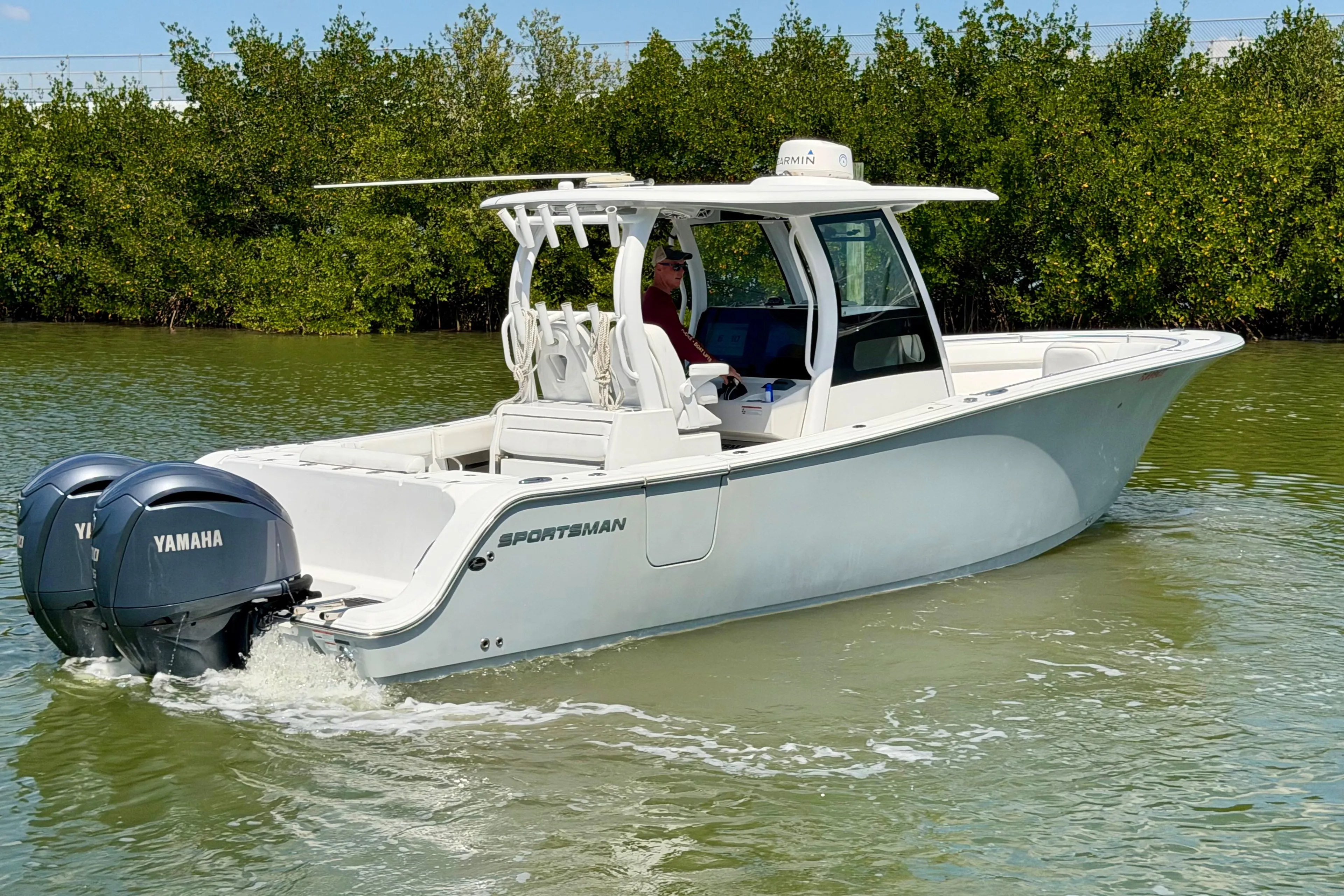 2021 Sportsman Open 302 Center Console boat cruising in calm waters with twin Yamaha engines.