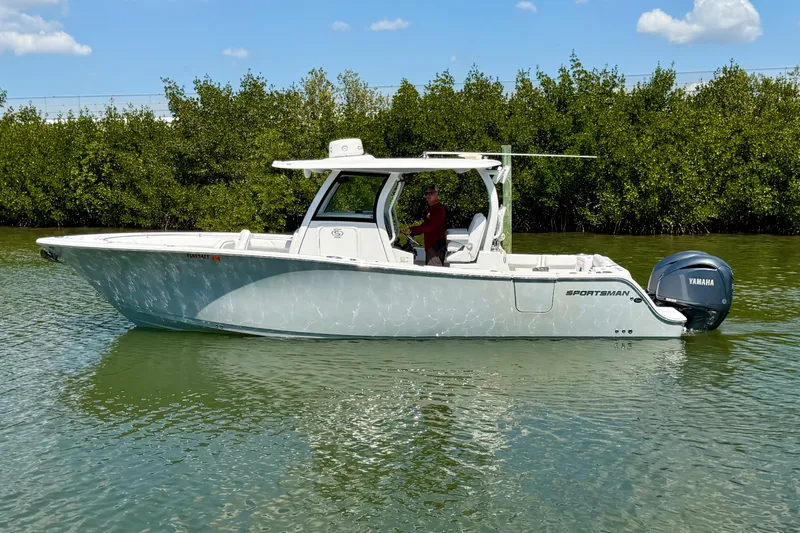  Yacht Photos Pics 2021 Sportsman Open 302 Center Console boat on calm water, surrounded by greenery.