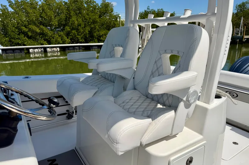  Yacht Photos Pics 2021 Sportsman Open 302 Center Console boat seats with armrests, docked near lush greenery.