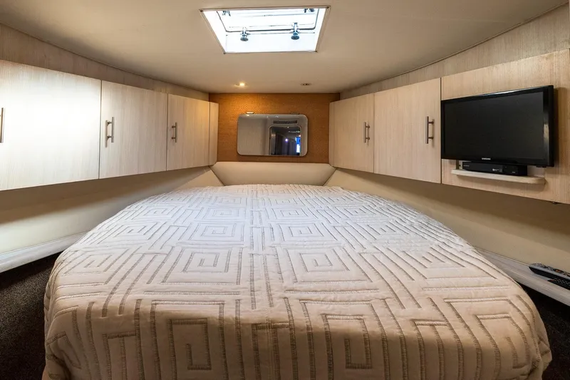 Falcon Yacht Photos Pics Luxurious cabin interior of 1998 Ocean Yachts 48 Super Sport with bed, TV, and storage cabinets.