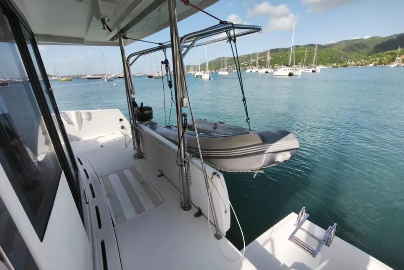  Yacht Photos Pics Catamaran deck with dinghy, overlooking a serene marina with sailboats.