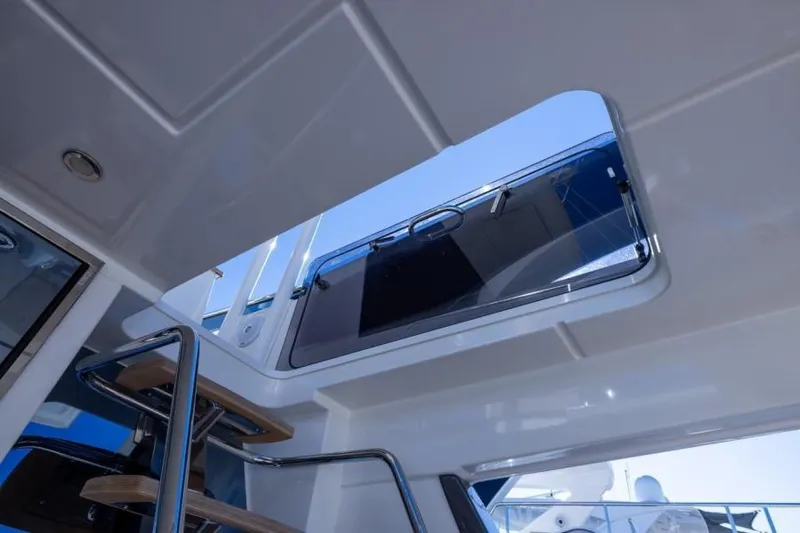 Osiris Yacht Photos Pics Interior view of 2022 Beneteau Monte Carlo 6 yacht with open sunroof and stairs.