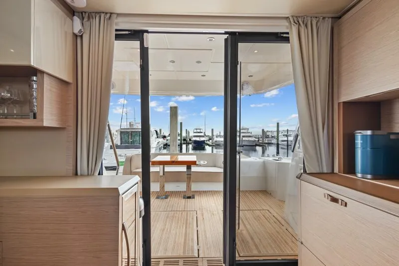 Osiris Yacht Photos Pics Interior view of 2022 Beneteau Monte Carlo 6 yacht, featuring elegant wood finishes and marina backdrop.