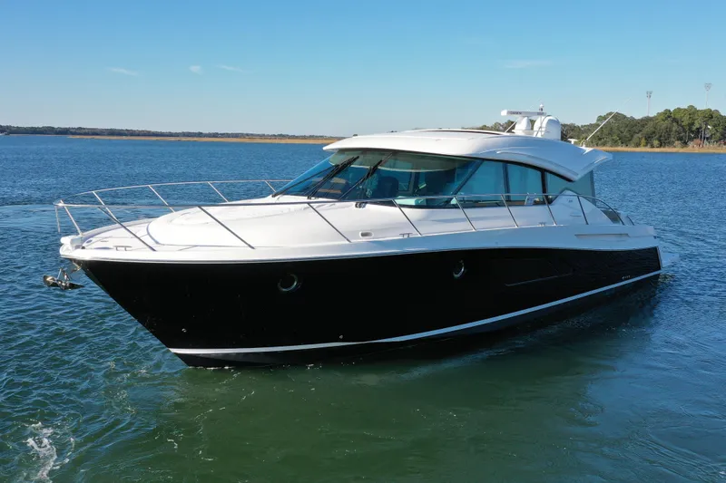  Yacht Photos Pics 2016 Tiara Yachts 50 Coupe cruising on a serene lake under a clear blue sky.