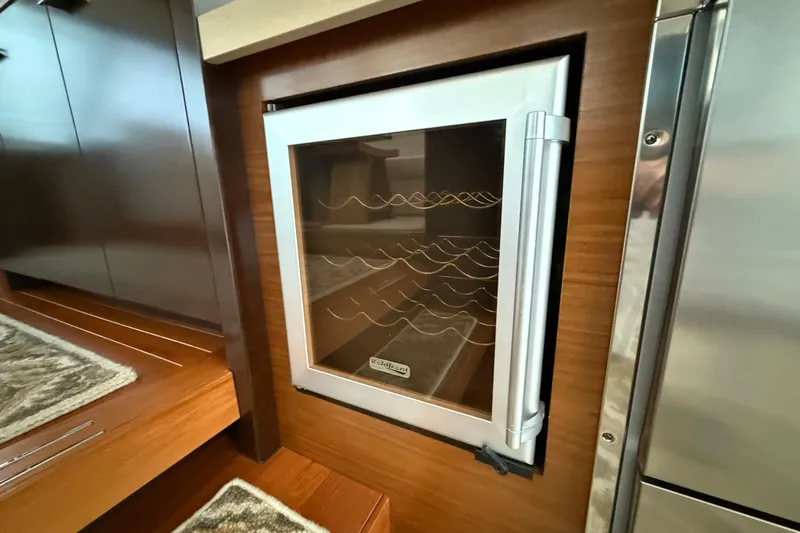  Yacht Photos Pics Built-in wine cooler on 2016 Tiara Yachts 50 Coupe, featuring wooden cabinetry and stainless steel accents.