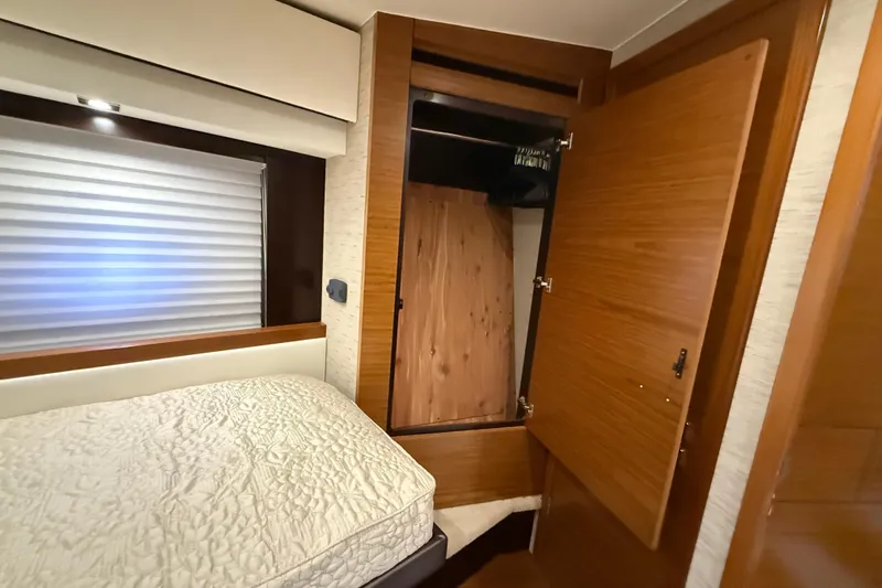  Yacht Photos Pics 2016 Tiara Yachts 50 Coupe interior with bed and open wooden closet.