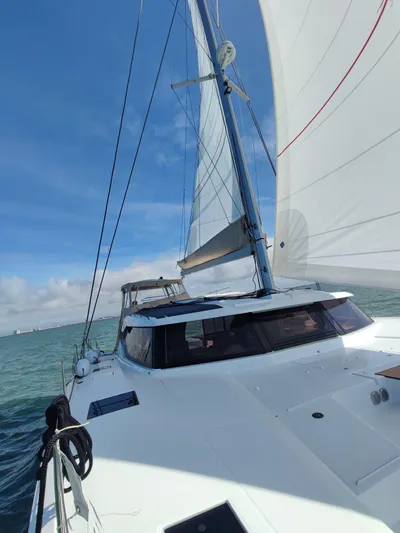  Yacht Photos Pics 2025 Fountaine Pajot Catamaran Aura 51 sailing on open water under clear blue skies.